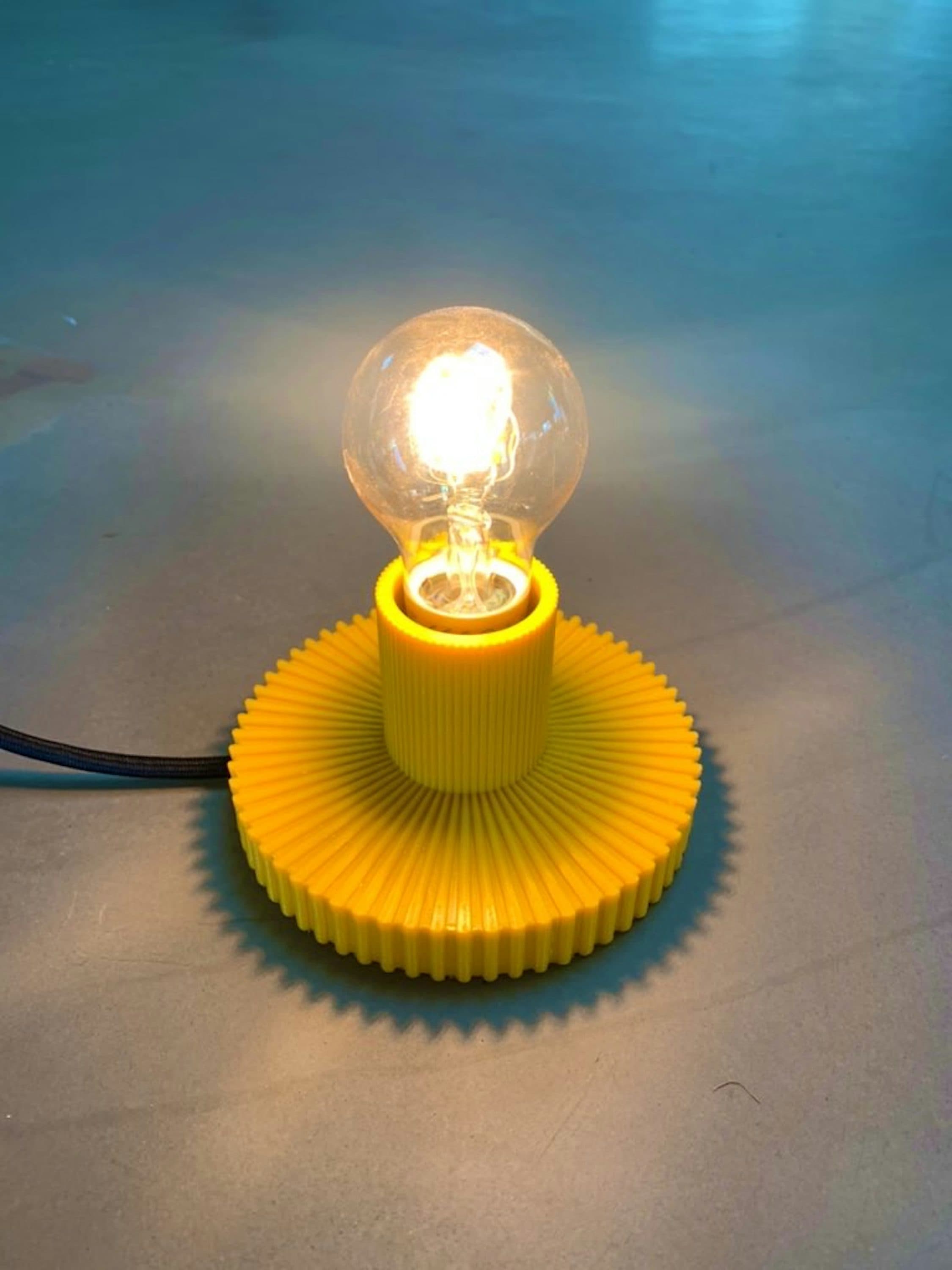 A glowing bulb in a bright yellow, ribbed ZwartsLAB lamp base